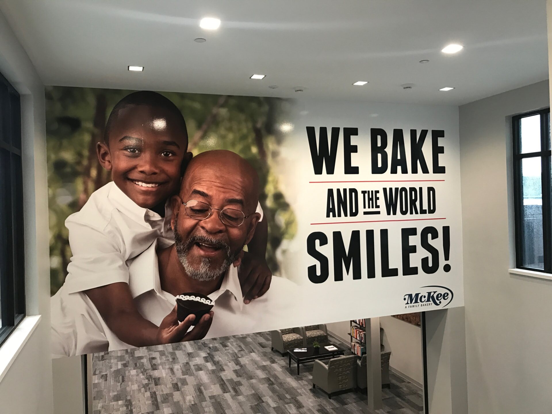 Large-format McKee Foods wall graphic reading “We bake and the world smiles!” in a bright interior lobby